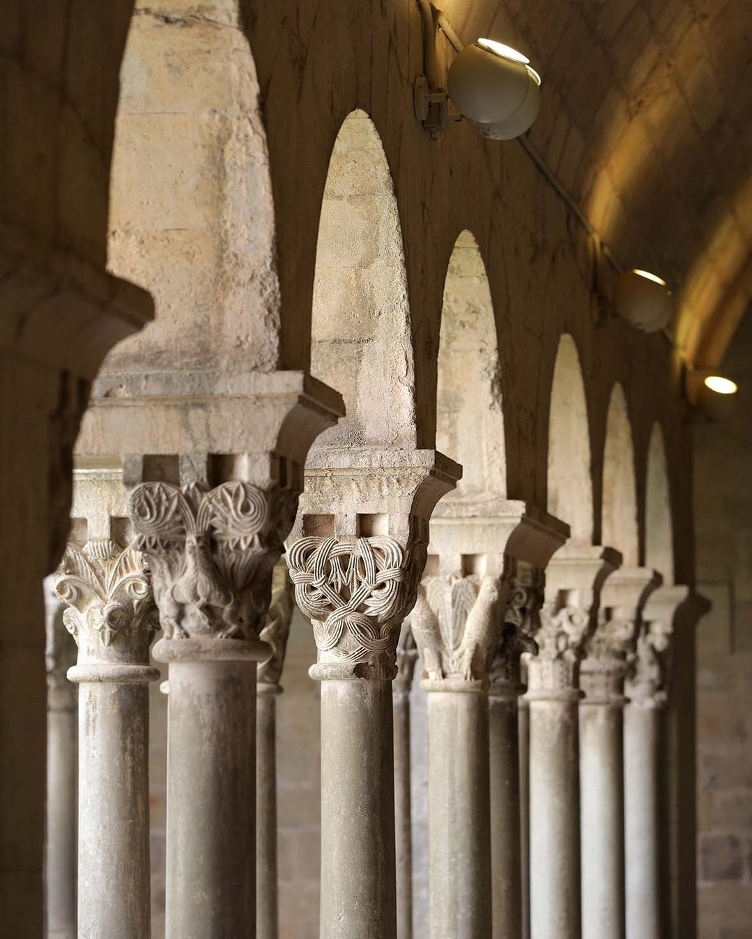 Dona observant el capitell d'una columna de claustre romànic