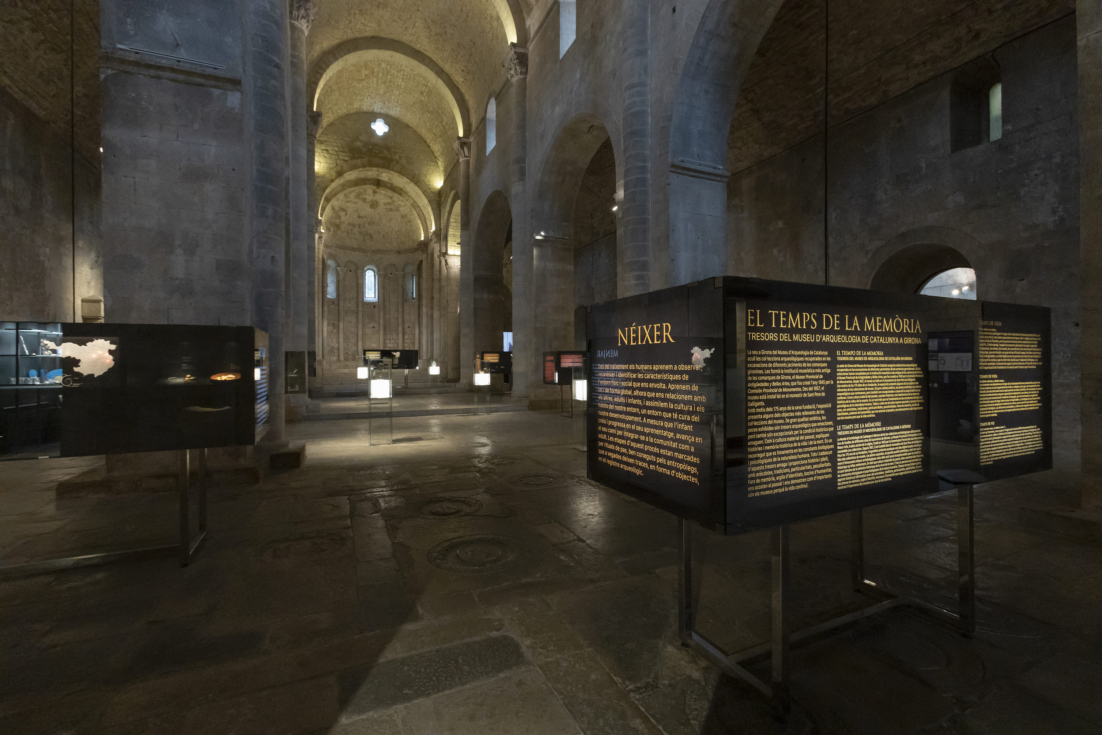 Interior d'una església romànica amb una exposició. 