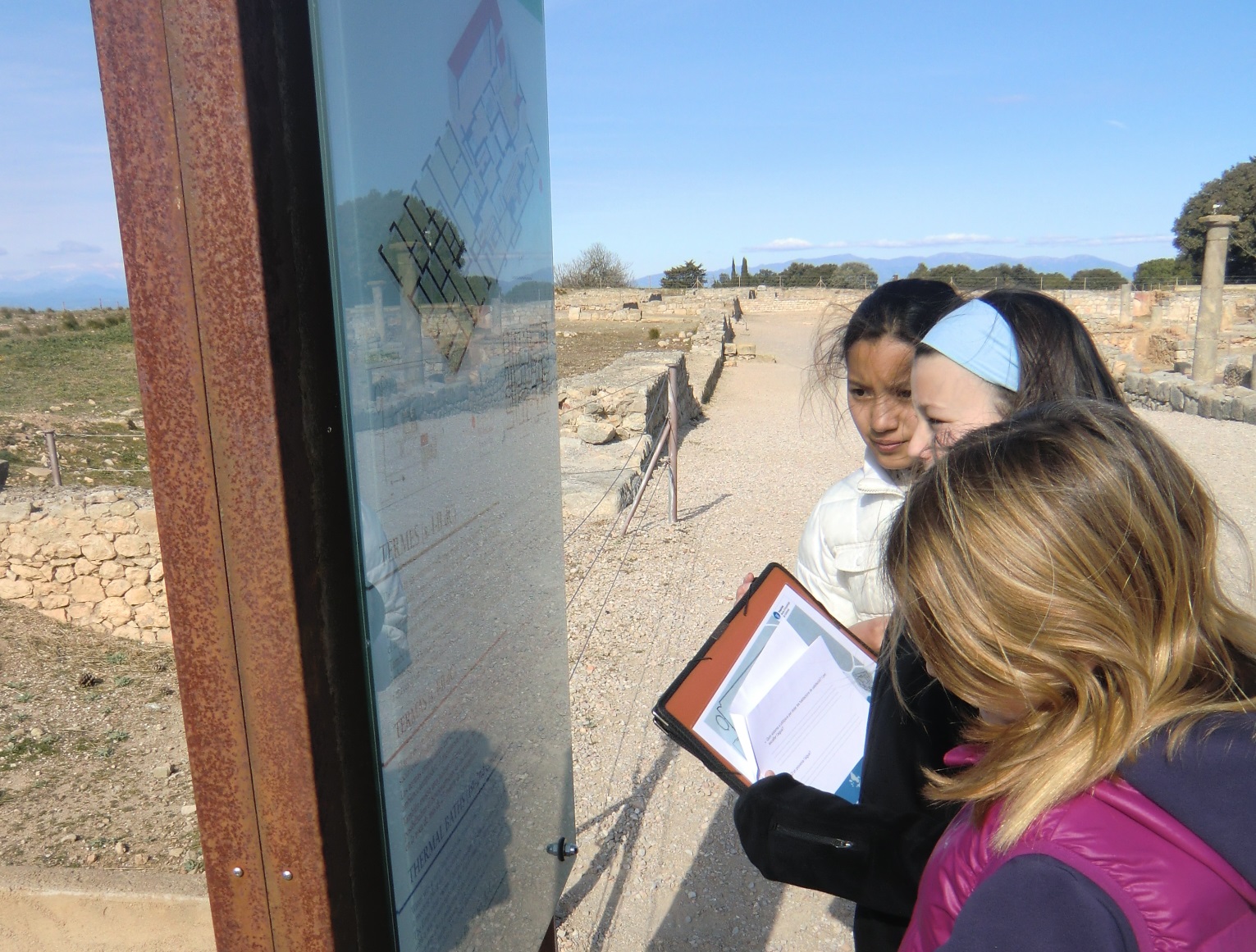 Tres noies llegint un plafó d'un jaciment.
