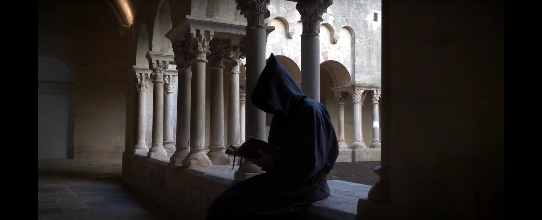 Monjo llegint en un claustre romànic.
