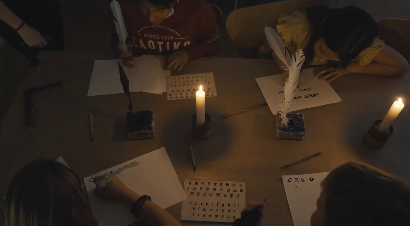 Infants escrivint amb ploma sobre paper antic.